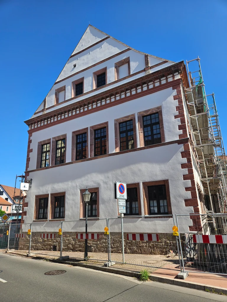 Seitenansicht des Rathauses Pegau während Renovierungsarbeiten, mit Natursteinarbeiten an der unteren Fassade.