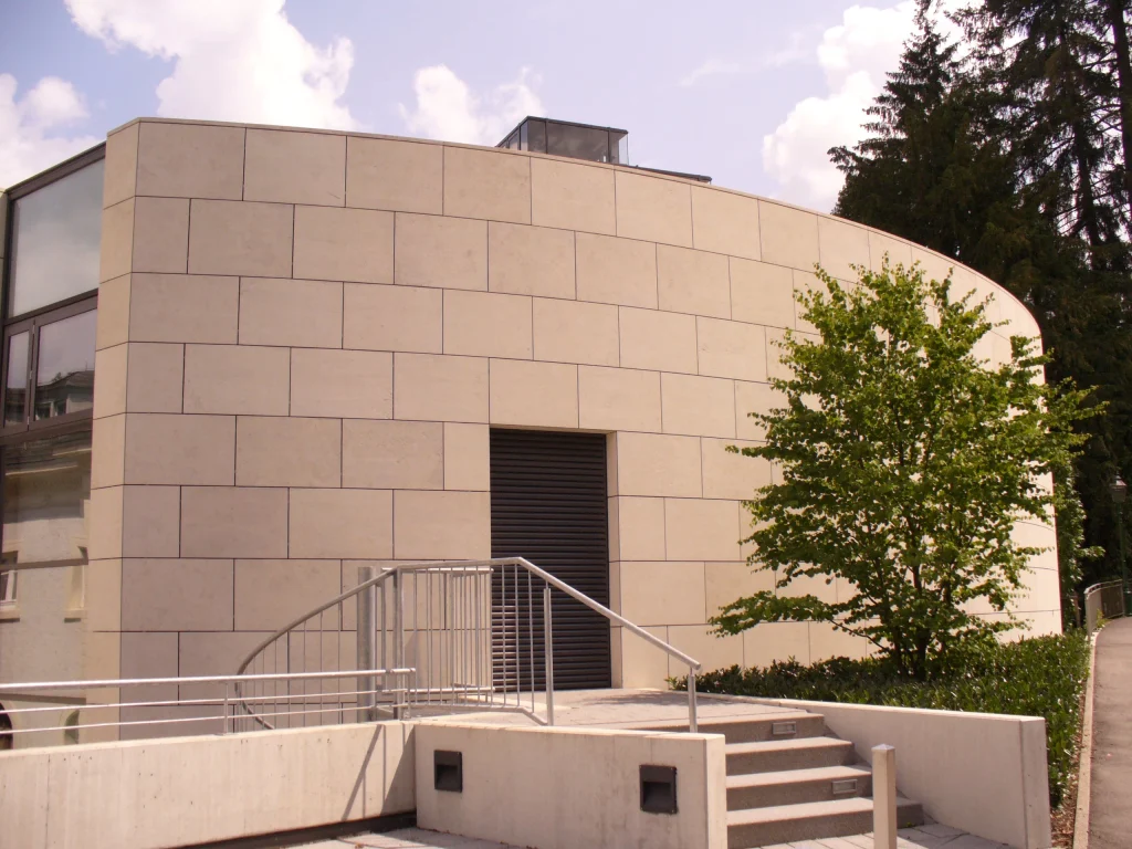 Gebäude mit abgerundeter Natursteinfassade, Treppenaufgang und Glasfenstern in Baden-Baden.